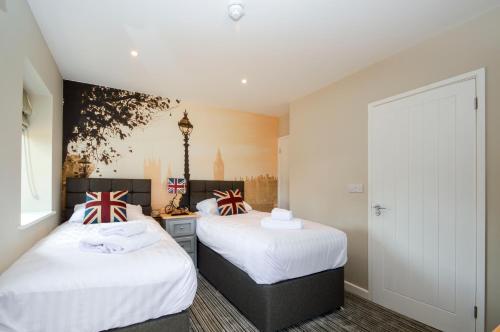 two beds in a room with white sheets at The Bell Inn in Newmarket