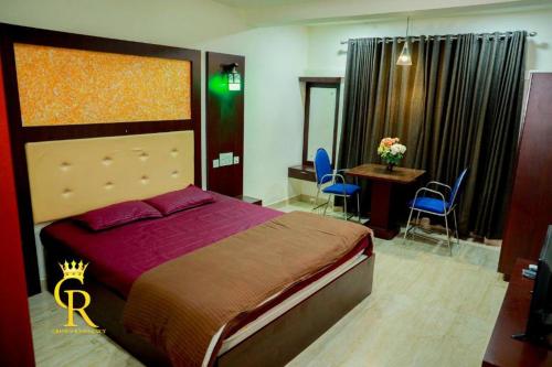 a bedroom with a bed and a table and chairs at Crown residency in Changanācheri