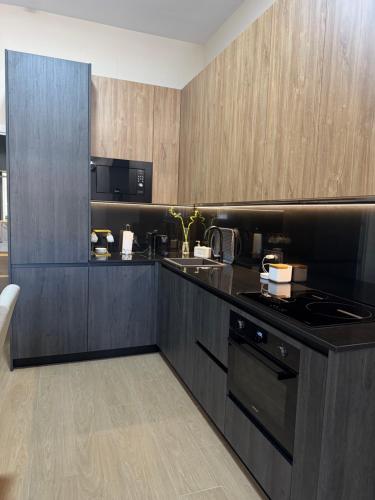 een keuken met zwarte werkbladen en houten kasten bij Apartamento Orilla de Triana Luxury in Sevilla