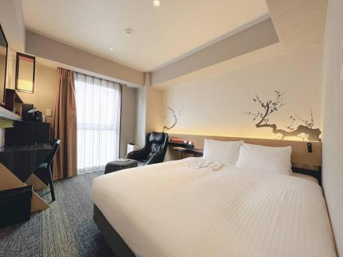 a hotel room with a large bed and a chair at Shizutetsu Hotel Prezio Kyoto Karasumaoike in Kyoto
