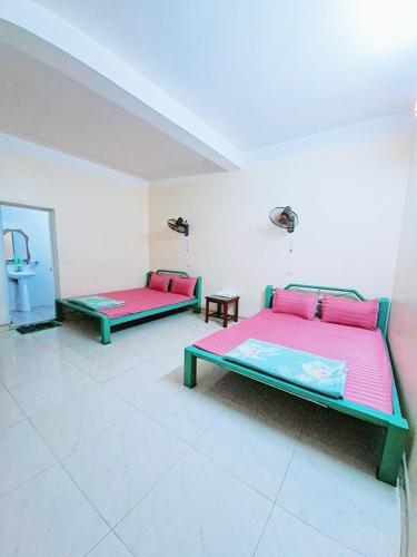 two beds in a room with pink and green at Nhà Nghỉ Đức Anh 2 in Ðại Sơn