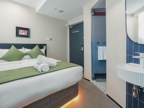 a bedroom with a bed and a bathroom with a sink at A Hotel Chinatown- Stay From 8PM To 9AM in Singapore