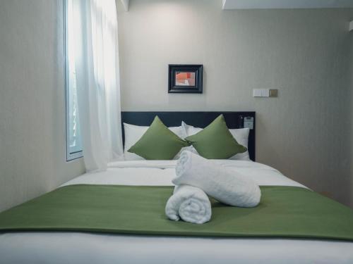 a bed with green and white towels on it at A Hotel Chinatown- Stay From 8PM To 9AM in Singapore