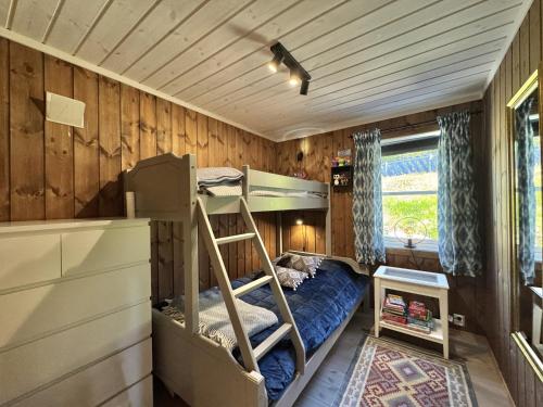 a bedroom with bunk beds in a wooden wall at Bjørnebo, Family cabin in Torpo
