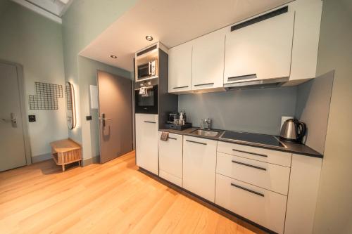 a kitchen with white cabinets and a wooden floor at HOP Apartments & Suites in Interlaken