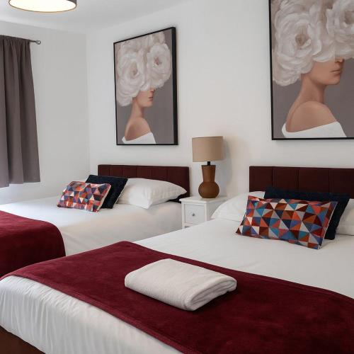 two beds in a bedroom with paintings on the wall at Halton haven Three bed house sleeps 8 in Halton