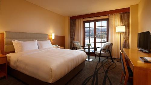 a hotel room with a bed and a desk and a television at Lotte Arai Resort in Myoko
