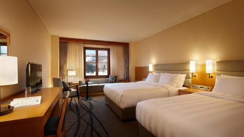 a hotel room with two beds and a television at Lotte Arai Resort in Myoko