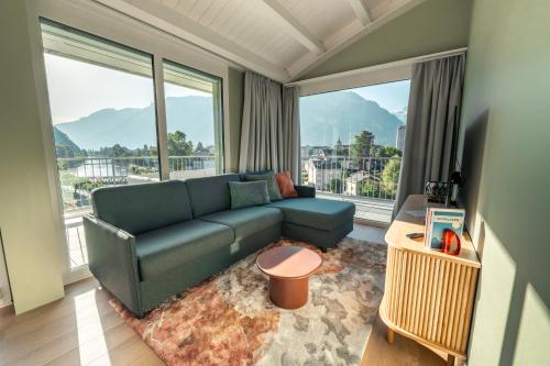 a living room with a blue couch and large windows at HOP Apartments & Suites in Interlaken