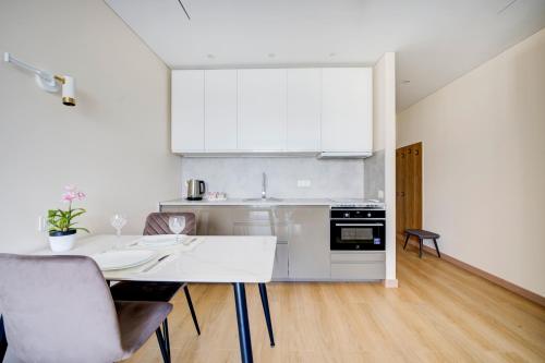 une cuisine blanche avec une table et des chaises dans l'établissement Pradoli apartament, à Vilnius