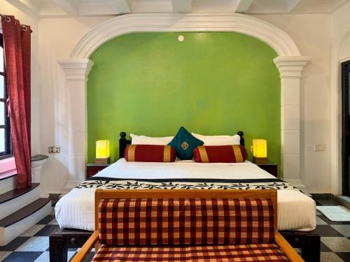 a bedroom with a large bed with a green wall at Le Chateau in Puducherry