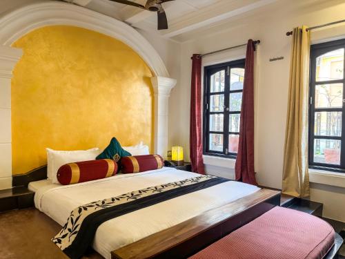 a bedroom with a large bed and two windows at Le Chateau in Puducherry