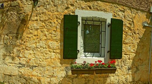 a window with green shutters and red flowers in a window box at Karmen's Apartment One in Split
