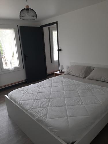 a large white bed in a bedroom with two windows at Appartement T1 bis proche centre ville in Figeac