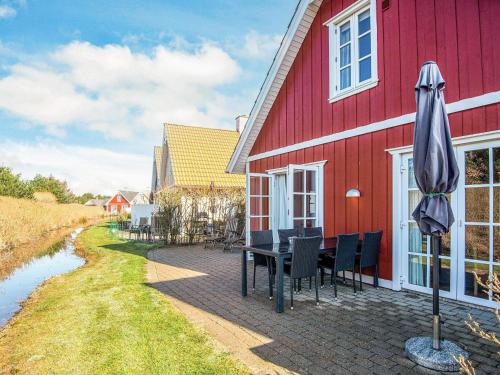 a red house with a table and chairs and an umbrella at Luxury Retreat in Blavand - By Traum Ferienwohnungen in Blåvand