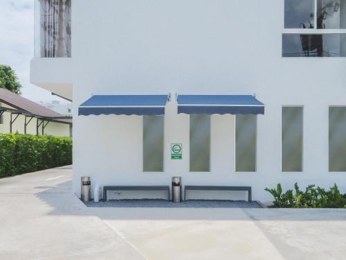 a white building with a blue awning on it at Samutprakarn Hotel in Samut Prakan