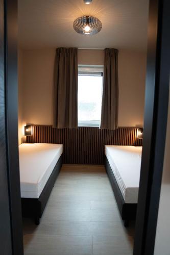 a room with two beds and a window at Camping Natuurlijk Limburg - Appartement in Voeren