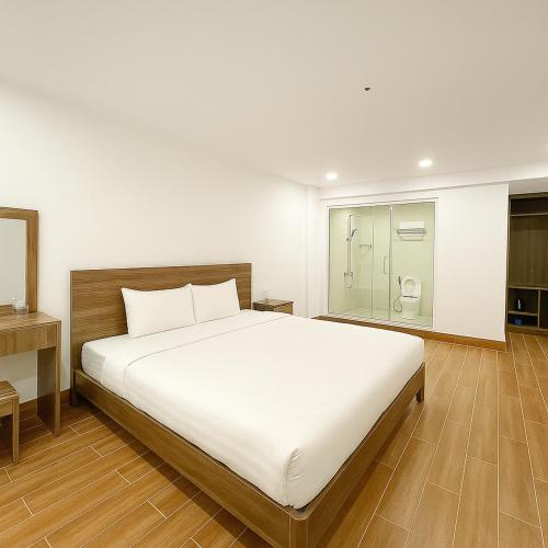 a bedroom with a large white bed and a bathroom at Thanh Thanh Station View in Da Lat
