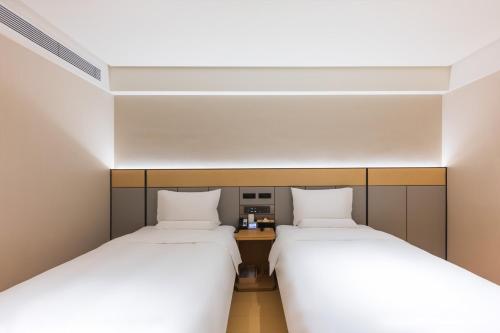 two beds in a small room with a desk between them at JI Hotel Beijing Andingmen Andeli North Street in Beijing