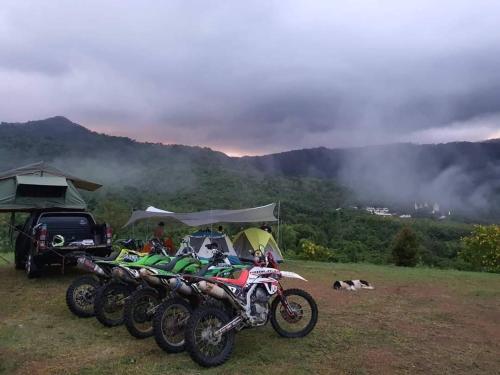 a group of motorcycles parked in a field with a mountain at Ruen Karlae in Ban Muang Ton Mamuang