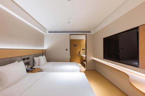 a hotel room with a large bed and a flat screen tv at JI Hotel Beijing Andingmen Andeli North Street in Beijing