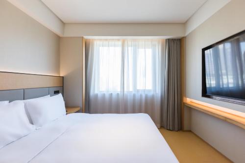 a hotel room with a bed and a television at JI Hotel Beijing Andingmen Andeli North Street in Beijing