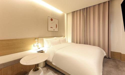 a hotel room with a white bed and a table at Yeongju Browndot Yeongju Jungang Branch in Yongju