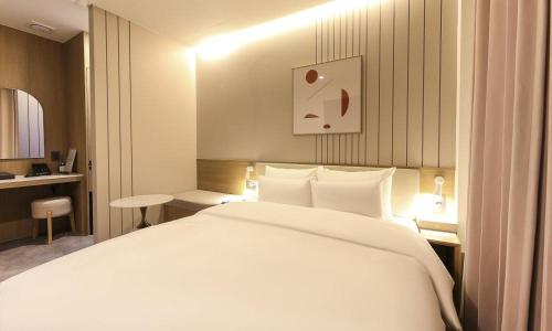 a bedroom with a large white bed and a desk at Yeongju Browndot Yeongju Jungang Branch in Yongju