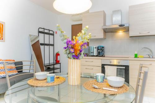 a kitchen with a glass table with a vase of flowers at Easy Hub Milano Malpensa Train Express in Gallarate
