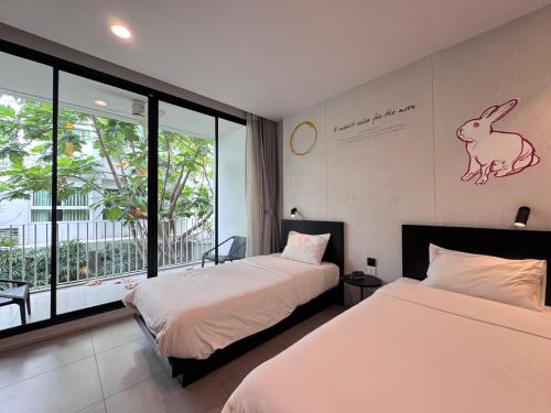 a hotel room with two beds and a window at CHERN Bangkok in Bangkok