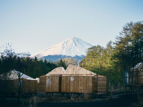 a snow covered mountain in the distance with wooden huts at SANU 2nd Home 河口湖2nd in Fujikawaguchiko