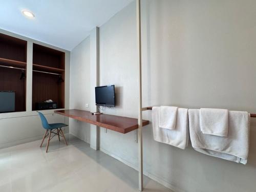 a room with a desk with a television and towels at CHERN Bangkok in Bangkok