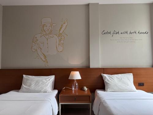 two beds in a hotel room with a drawing on the wall at CHERN Bangkok in Bangkok