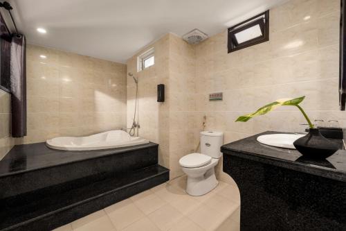 a bathroom with a tub and a toilet and a sink at Grand Fusion Point Hotel in Hue