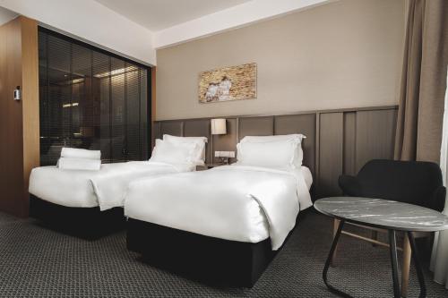 a hotel room with two beds and a table at WEIL Hotel Ipoh in Ipoh