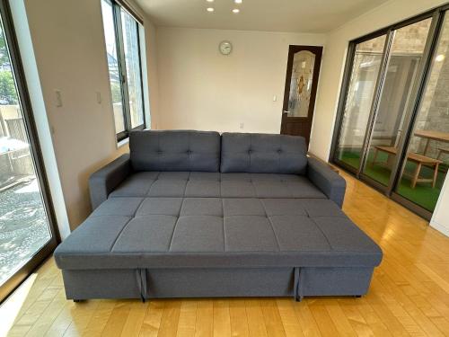 a large blue couch in a room with windows at リゾートヴィラ宮島 Sunset terrace in Hatsukaichi