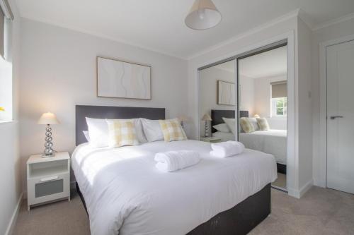 a white bedroom with two beds and a mirror at Modern 2-Bedroom Home near Glasgow & Edinburgh in Airdrie