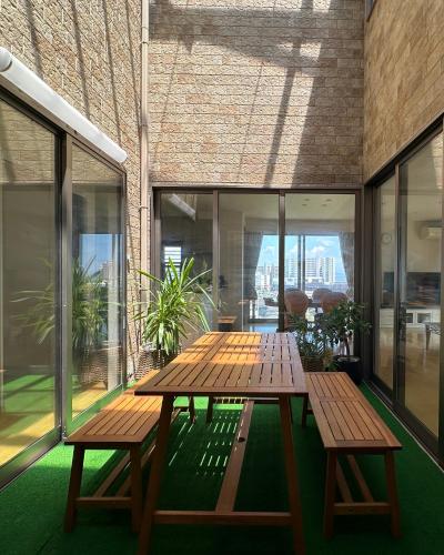 a wooden picnic table on a balcony with windows at リゾートヴィラ宮島 Sunset terrace in Hatsukaichi