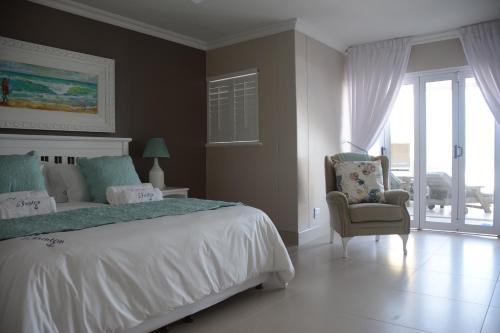 a bedroom with a bed and a chair and a window at Frinton on Sea4 in Ballito