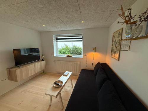 ein Wohnzimmer mit Sofa und Fernseher in der Unterkunft Small cozy rental unit in Strendur Centre in Strendur