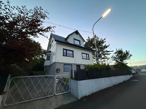 ein weißes Haus mit einem Tor davor in der Unterkunft Small cozy rental unit in Strendur Centre in Strendur