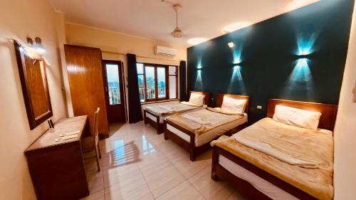 a room with three beds and a sink and windows at Thebes Hotel in Luxor