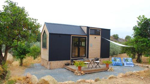a tiny house with a black roof and two chairs at La Vista Huma by Tiny Away in Alora
