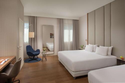 a hotel room with a bed and a desk and a chair at NH Bologna De La Gare in Bologna