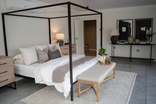 a bedroom with a large canopy bed with a table at Kénōsis Guestfarm- Two Bedroom Apartment in Springbok