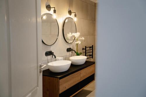 a bathroom with two sinks and two mirrors at Kénōsis Guestfarm- Two Bedroom Apartment in Springbok