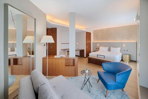 a hotel room with a bed and a blue chair at NH Bologna De La Gare in Bologna