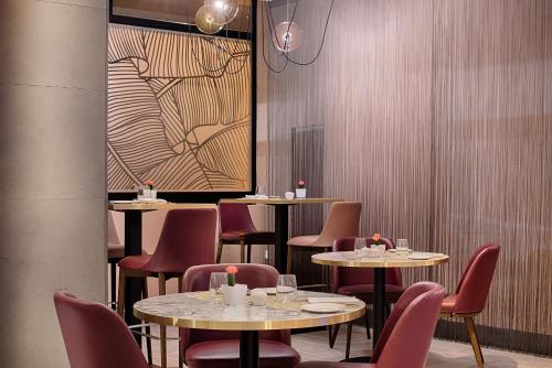 a restaurant with tables and chairs and a painting on the wall at NH Bologna De La Gare in Bologna