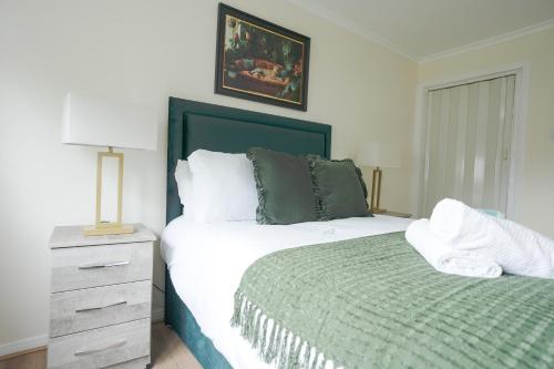 een slaapkamer met een bed en een dressoir met een groene deken bij 2 BDR Apt At Caledonia Luxe Stays Short Lets & Serviced Accommodation Airdrie in Airdrie