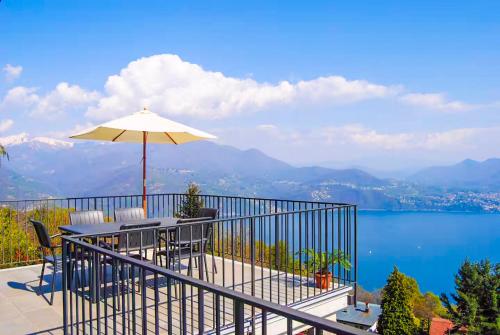 a balcony with a table and an umbrella at Perla del Lago in Carmine